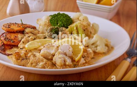 Curry-Zitronenfischfilets in einer Zitronensauce mit Gemüse und frittierten Süßkartoffelscheiben. Stockfoto