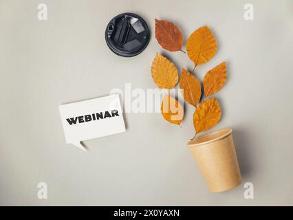 Ein weißes Schild mit der Aufschrift „Webinar“ wird neben einer Topfpflanze mit Blättern platziert Stockfoto