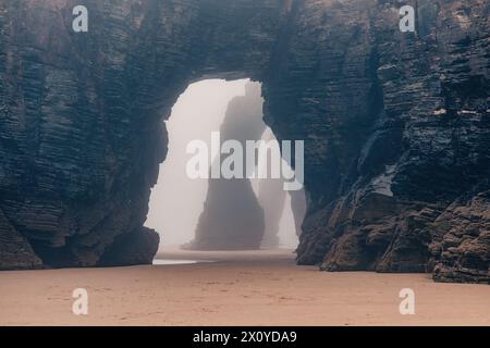 Playa de Las Catedrales bei Nebel. Catedrais Strand in Ribadeo, Lugo, Galicien, Spanien. Natürliche Bögen des Cathedrals Strandes. Moody Rock Formationen auf Stockfoto