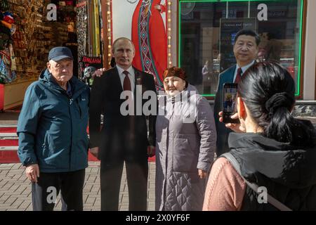 Moskau, Russland. April 2024. Ein Paar steht neben einem Pappbild, das den russischen Präsidenten Wladimir Putin in der touristischen Arbat-Straße in der Moskauer Innenstadt zeigt Stockfoto
