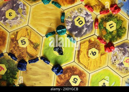 Mozyr, Weißrussland, 1. April 2024: Ein catan-Brettspiel mit blauen, grünen und roten Chips von Spielern auf dem Spielfeld. Blockierte Ressource Hex von Banditen. Das längste High Stockfoto