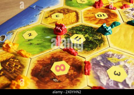 Mozyr, Weißrussland, 1. April 2024: Ein catan-Brettspiel mit grünen, roten und grünen Chips von Spielern auf der Karte. Rote und schwarze Zahlen auf der Karte. Gute und schlechte Hex Stockfoto