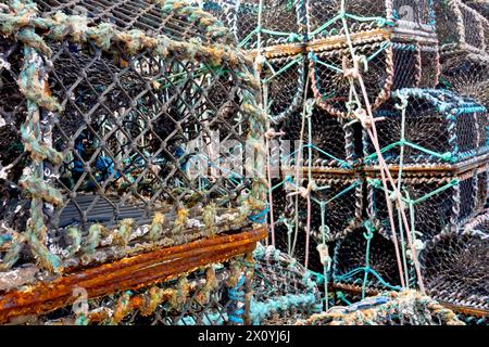 Nahaufnahme von Kreelen, Krabben- oder Hummertöpfen, die im Winter an der Küste des Hafens Arbroath in Schottland, Großbritannien, aufeinandergestapelt sind. Stockfoto