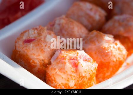 Gebackene Sushi-Brötchen mit Lachs, Käse und Sauce auf einem geschäumten Polystyrol-Tablett aus nächster Nähe. Stockfoto