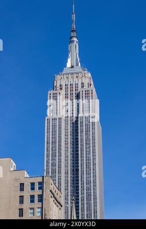Empire State Building im Sonnenlicht vor blauem Himmel Stockfoto