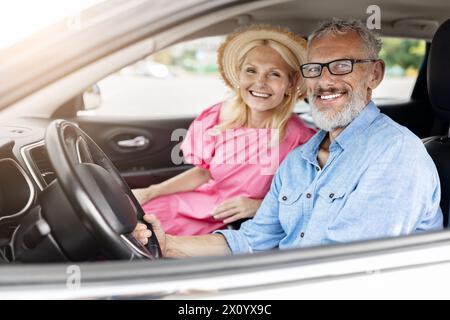 Glückliches älteres Paar im Auto mit Fenster nach unten Stockfoto