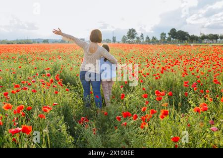 Rückansicht von Mutter und Tochter, die im Mohnfeld umarmt stehen Stockfoto