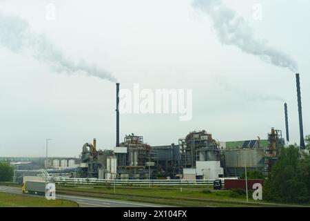 Eine Fabrik, die Rauch aus ihren hohen Stapeln in den Himmel bläst, zeigt industrielle Aktivität und Verschmutzung. Stockfoto