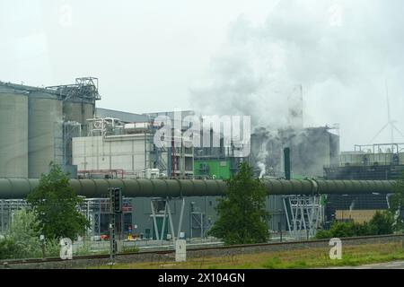 Eine Fabrik, die Rauch aus ihren hohen Stapeln in den Himmel abgibt, was auf aktive industrielle Prozesse und Verschmutzung hinweist. Stockfoto