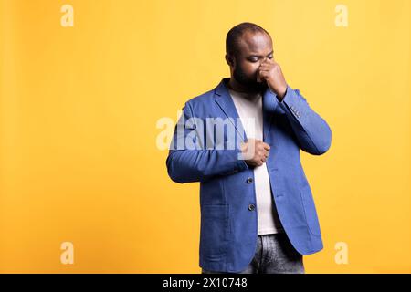 afroamerikanischer Mann, der sich im Winter kalt macht, isoliert über Studiohintergrund. BIPOC-Person, die an Grippe leidet, Probleme mit einer Sinusinfektion hat Stockfoto