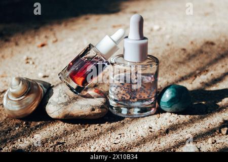 Anti-Aging-Serum-Pipettenflaschen auf einem Steinpodium. Dekorative Kosmetik auf beigefarbenem Sandhintergrund mit Palmenschatten. Weibliche Hautpflege-Routine. Stockfoto