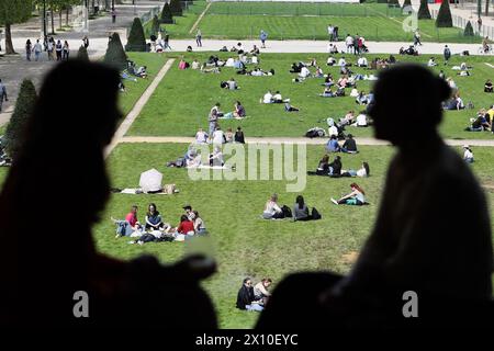 Paris, Frankreich. April 2024. Dieses am 14. April 2024 aufgenommene Foto zeigt Menschen, die die Sonne auf den Champs de Mars am Fuße des Eiffelturms in Paris genießen.Foto: Thibaud MORITZ/ABACAPRESS.COM Credit: Abaca Press/Alamy Live News Stockfoto