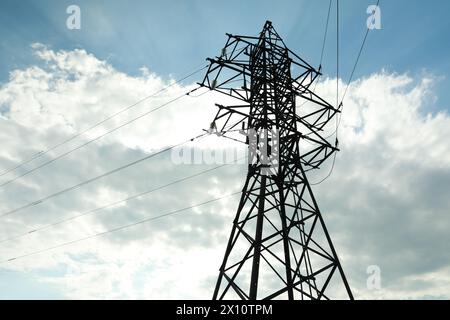 Telefonmast und Kabel gegen blauen Himmel mit Wolken Stockfoto