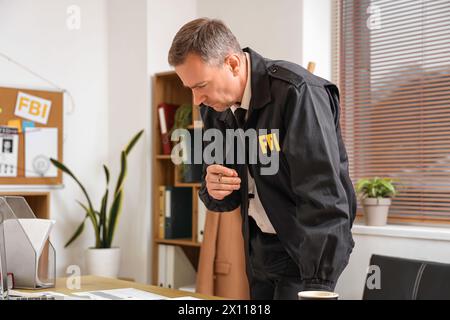 Ein reifer FBI-Agent arbeitet am Tisch im Büro Stockfoto