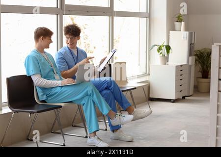 Männliche Assistenzärzte mit Laptop im Kliniksaal Stockfoto