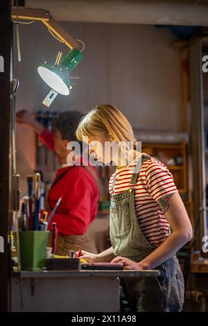 Fokussierte Zimmermannin erstellt eine Schätzung für die Herstellung von handgefertigten Möbelständern in der Tischlerei Stockfoto