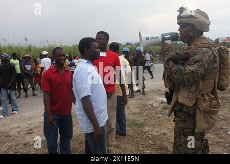 Staff-Sgt. Clausele Barthold, Linguist beim Battalion Landing Team, 3. Bataillon, 2. Marine Regiment, 22. Marine Expeditionary Unit, spricht mit lokalen Haitianern während einer Operation zur Versorgung der Bevölkerung von Leogane mit Nahrung und Wasser, 19. Januar 2010. Stockfoto