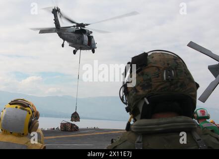 Ein Navy MH-60S Night Hawk von der Helicopter Sea Combat Squadron 22 hebt die USS Bataan mit Vorräten während der Mission der 22nd Marine Expeditionary Unit in Haiti am 19. Januar 2010 ab. Die 22. MEU ist an Bord der Schiffe der Bataan Amphibious Ready Group in der Nähe der Insel Haiti angelaufen, um humanitäre Hilfe und Katastrophenhilfe nach einem verheerenden Erdbeben, das das Land heimgesucht hat, zu leisten. Stockfoto