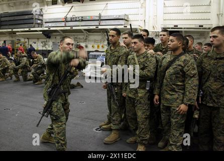 First Lt. Byron McCoy, ein Zugkommandant bei Kompanie L, Battalion Landing Team, 3. Bataillon, 2. Marine Regiment, 22. Marine Expeditionary Unit, bringt Marines aus seiner Kompanie die richtigen Verfahren bei, um auf einen Aufstand zu reagieren, während sie an Bord der USS Bataan am 17. Januar 2010 waren. Die Marines wurden für mögliche Situationen geschult, auf die sie stoßen könnten, bevor sie nach Haiti aufbrachen, um die Operation Unified Response zu unterstützen. Stockfoto