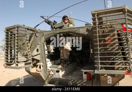 Von der Luke eines Stryker-Fahrzeugs aus sichert Brian Weinberger seinen Feuersektor in Al Kut, Irak, mit einem M240B-Maschinengewehr. Als Mitglied des 1. Bataillons, 23. Infanterieregiments, ist Weinberger einer der ersten Soldaten, die das Stryker-Fahrzeug, ein achträdriges gepanzertes Fahrzeug, eingesetzt haben. August 2004 Stockfoto
