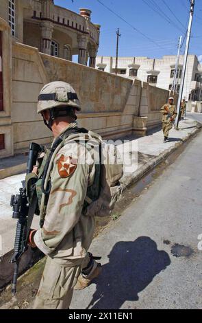 SPC. Eric Smith überprüft Soldaten der irakischen Nationalgarde während einer Patrouille in Mossul. Obwohl Sicherheitsoperationen an die irakischen Sicherheitskräfte weitergegeben wurden, arbeiten die multinationalen Streitkräfte weiterhin mit ihren irakischen Waffenbrüdern zusammen. Juni 2004 Stockfoto