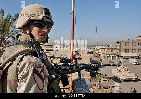 Sgt. Nicholas Bayers, Ein Co, 2-5 Cav, beobachtet die Straßen von Sadr City vom Dach eines Gebäudes, das gerade von Mitgliedern der Task Force Lancer durchsucht wurde. Die Task Force Lancer ist in die zweite Woche der Operation Iron Fury eingezogen, eine Operation, die dazu dient, Gebiete innerhalb der ärmsten Nachbarschaft Baghdads für zivile militärische Operationen zu sichern. August 2004 Stockfoto