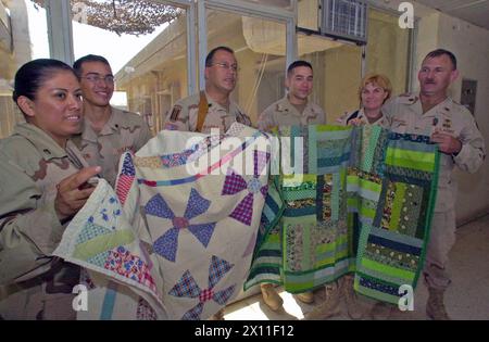 Soldaten von LSA Anaconda's Civil Affairs (Staff Sgt. Margie Chapman, SPC. Jason Aragon, Lt. Colonel Felipe Ibarra, Sgt. David Soliz, Major Kristi Hilton und Major Lancaster) halten zwei der vier Quilts, die von Piecing for Peace gespendet wurden, für die Übersetzer, die sie bei den Beziehungen in der Nähe von Balad, Irak, unterstützen. 2004 Stockfoto