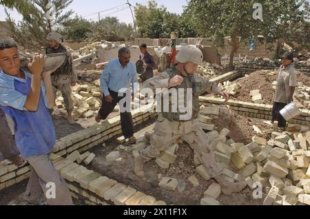 Oberstleutnant Robert Cody, Kommandant des 118. Medizinischen Bataillons, springt über Ziegel, während er die Baustelle der neuen medizinischen Klinik besucht, die seine Einheit in Al Anwar Village, Irak, CA. Juni 2004. Stockfoto