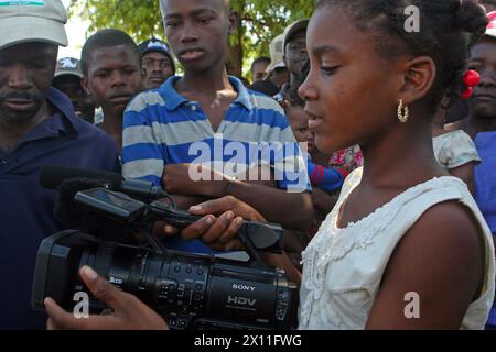 Ein Kind aus Cotes de Fer, Haiti, spielt mit einer Videokamera an einem temporären Hilfsverteilungspunkt, 21. Januar 2010. Marines und Seeleute aus der 22. MEU errichteten in der Nähe von Cotes de Fer (Haiti) eine vorübergehende Verteilung von Hilfsgütern, die Wasser und Nahrungsmittel in Flaschen für die Verteilung an die Binnenvertriebenen Haitianer brachten. Die 22. MEU, die an Bord der Schiffe der Bataan Amphibious Ready Mission gegangen ist, wird zur Unterstützung der Hilfseinsätze in Haiti eingesetzt. Stockfoto