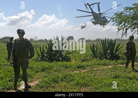 Marines von der Weapons Company, Battalion Landing Team, 3. Bataillon, 2. Marine Regiment, 22. Marine Expeditionary Unit, richteten einen Sicherheitsumkreis ein, während zwei Super-Hengst-Helikopter CH-53E aus der Marine Heavy Helicopter Squadron 461 (verstärkt) von Cotes de Fer, Haiti starten, 21. Januar 2010. Marines und Seeleute aus der 22. MEU errichteten in der Nähe von Cotes de Fer (Haiti) eine vorübergehende Verteilung von Hilfsgütern, die Wasser und Nahrungsmittel in Flaschen für die Verteilung an die Binnenvertriebenen Haitianer brachten. Stockfoto