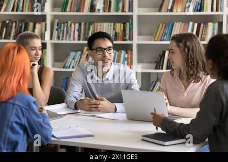 Verschiedene Studenten tauschen Ideen aus, die sich in der Teamarbeit in der Universitätsbibliothek engagieren Stockfoto