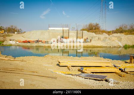 Provisorische Lagerung im Freien, Dielen, Balken auf dem Boden gestapelt, gestapelte Holzprofile für die Notwendigkeit, eine Brückenform zu bauen, über den Fluss sind Brücke Stockfoto