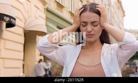 Junge kaukasische unglückliche Frau mit Kopf Kopfschmerzen Problem ungesund müde weibliche Angst berührende Krankheit Migräne schmerzhaftes Leiden Unwohlsein Augen Stockfoto