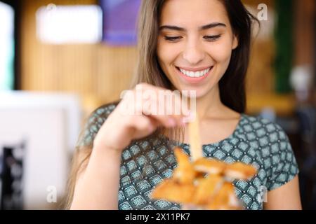 Vorderansicht Porträt einer glücklichen Frau, die in einem Restaurant Hühnerfinger isst Stockfoto