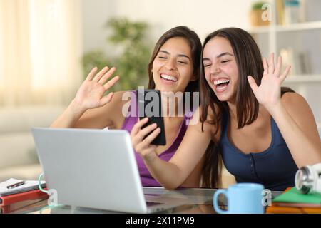 Zwei glückliche Schüler, die zu Hause telefonieren Stockfoto