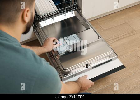 Mann, der Waschmitteltablette in den offenen Geschirrspüler steckt, Nahaufnahme Stockfoto