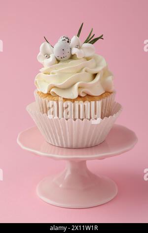 Leckerer Oster-Cupcake mit Vanillecreme auf rosa Hintergrund Stockfoto