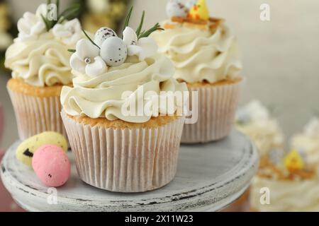 Leckere Ostercupcakes mit Vanillecreme und Süßigkeiten auf Kuchenständer, Nahaufnahme Stockfoto