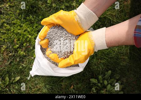 Frau mit Dünger auf grünem Gras draußen, Blick von oben Stockfoto