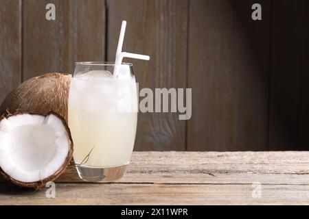 Glas Kokoswasser, Eiswürfel und Nüsse auf Holztisch, Platz für Text Stockfoto