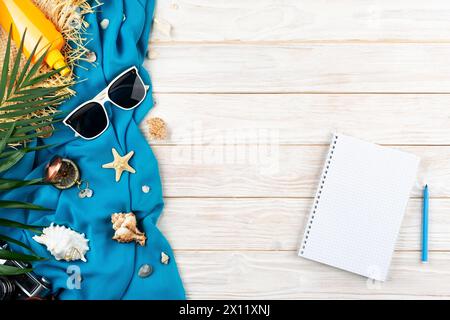 Hintergrund der Urlaubsplanung mit Notizbüchern, Seesternen, Sonnenbrillen, Kompass, Kamera und Strohhut auf blauem Stoff und weißen Dielen, die flach liegen Stockfoto