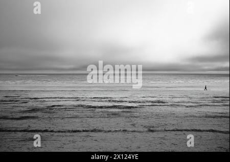 Ein einsamer Wanderer am Bridlington Beach bei Ebbe in Schwarz-weiß Stockfoto