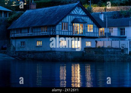 Abendlicht im Warfleet Creek. Haus Lichter und Wasser Reflektionen von einem Riverside Cottage, Dartmouth Stockfoto