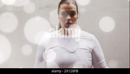 Bild von Lichtflecken über der Größe der kaukasierin in Sportkleidung, die Muskeln beugt Stockfoto