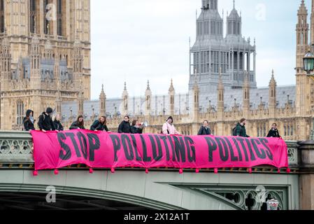 London, Großbritannien. 15. April 2024. Klimaaktivisten von Climate Resistance werfen ein Banner von der Westminster Bridge mit der Aufschrift „Stop Poluting Politics“. Anrede: Andrea Domeniconi/Alamy Live News Stockfoto