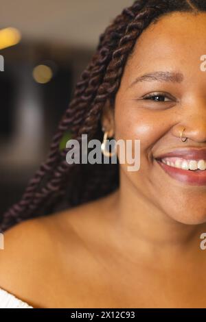 Eine junge Frau, die eine Rasse hat, lächelt, trägt Nasenring und Creolen, in einem modernen Geschäftsbüro Stockfoto