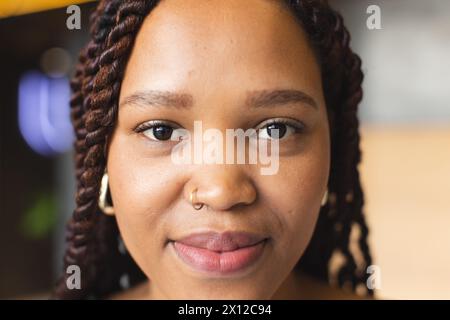 Eine junge Frau mit geflochtenen Haaren sieht in einem modernen Geschäftsbüro in die Kamera Stockfoto