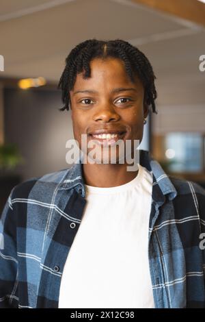 Afroamerikaner trägt kariertes Hemd über weißem T-Shirt und lächelt Stockfoto