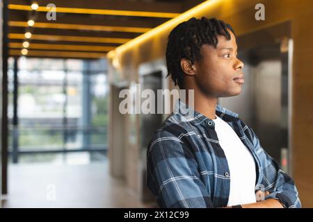 Afroamerikaner steht, sieht nachdenklich aus in einem modernen Geschäftsbüro mit Kopierraum Stockfoto