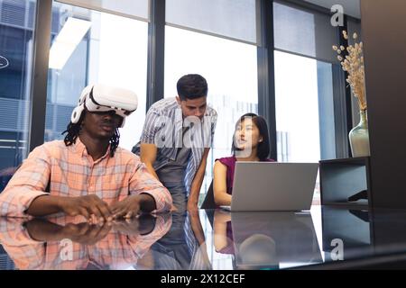 Verschiedene Kollegen erkunden virtuelle Realität und nutzen Notebooks in einem modernen Geschäftsbüro Stockfoto